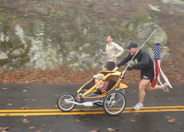 man running with baby stroller